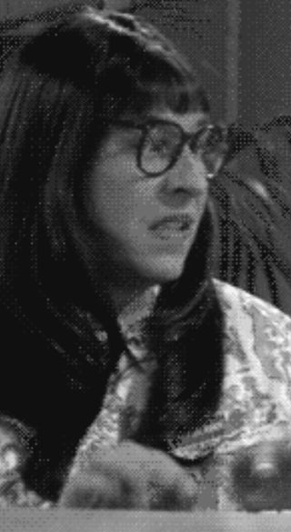 Screenshot aus Little Britain. Eine Frau mit langem braunen Haar und Brille sitzt an einem Schreibtisch und tippt etwas in einen Computer.