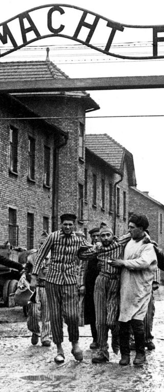 Soviet soldiers guide prisoners of the concentration camp Auschwitz-Birkenau out of its main gate, following the liberation of Auschwitz on January, 27 1945. Above the gate the motto «Arbeit macht frei» is visible.