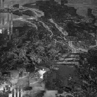 A close-up photo of red and black lava flowing down a brown stony shallow slope, but the image is slightly distorted by digital artefacts.